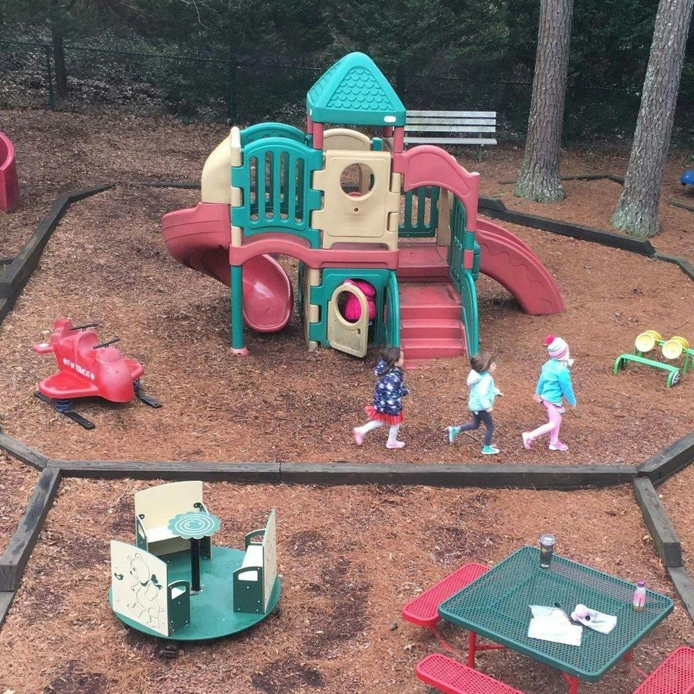 Three children walking on a playground with play structures