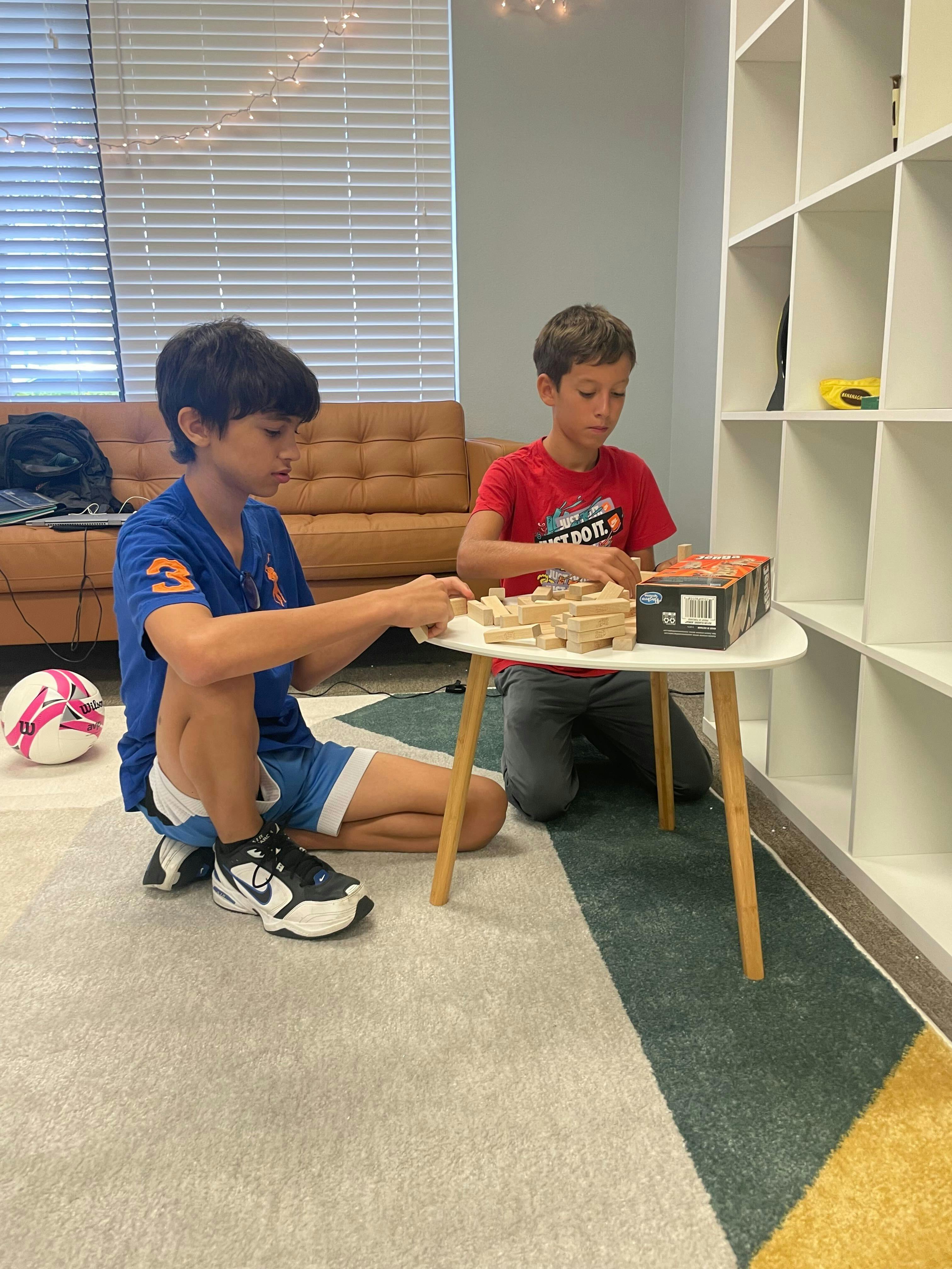 Two children playing with building blocks on a small table