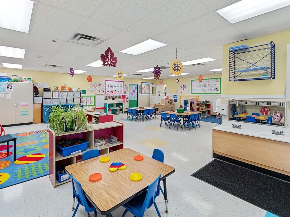 Classroom with small tables and chairs, toys, and supplies