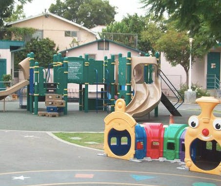 Playground with green and tan play structure and colorful tunnel