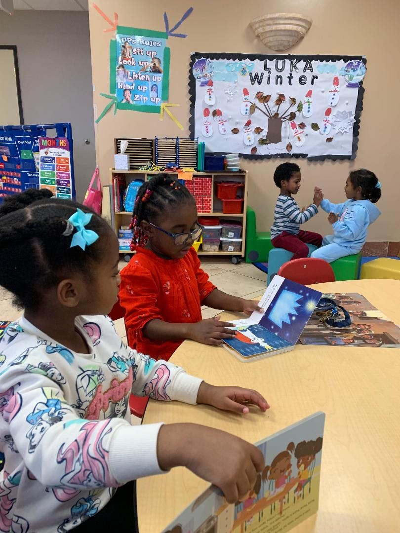 Children reading books at a table in a classroom