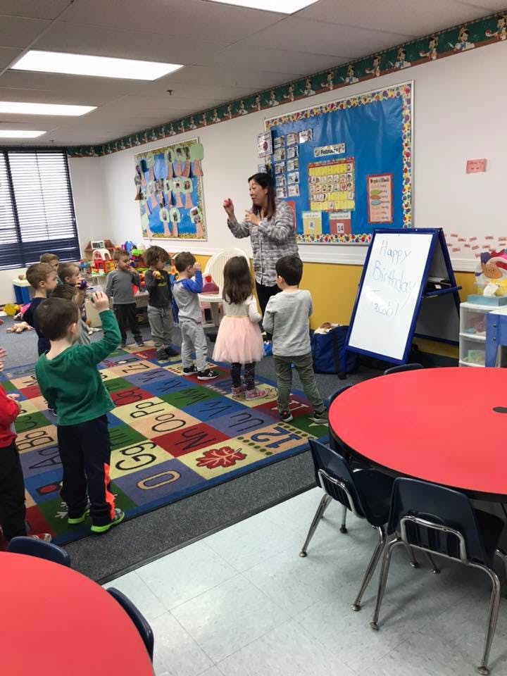 Person leading a group of children in a classroom