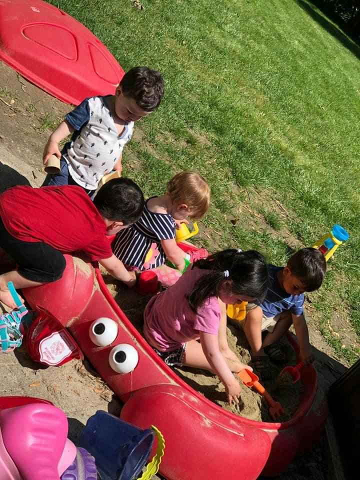 Children playing in a sandbox with toys