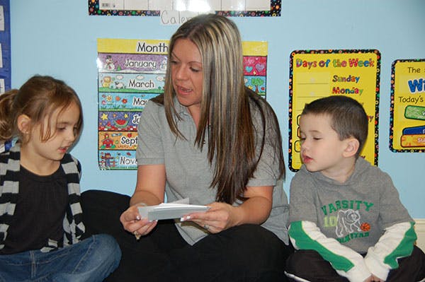 Person reading to two children in a classroom