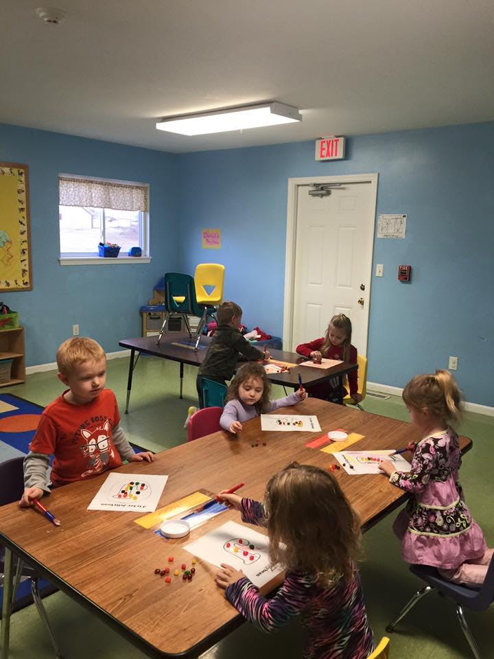 Children sitting at tables doing crafts in a classroom
