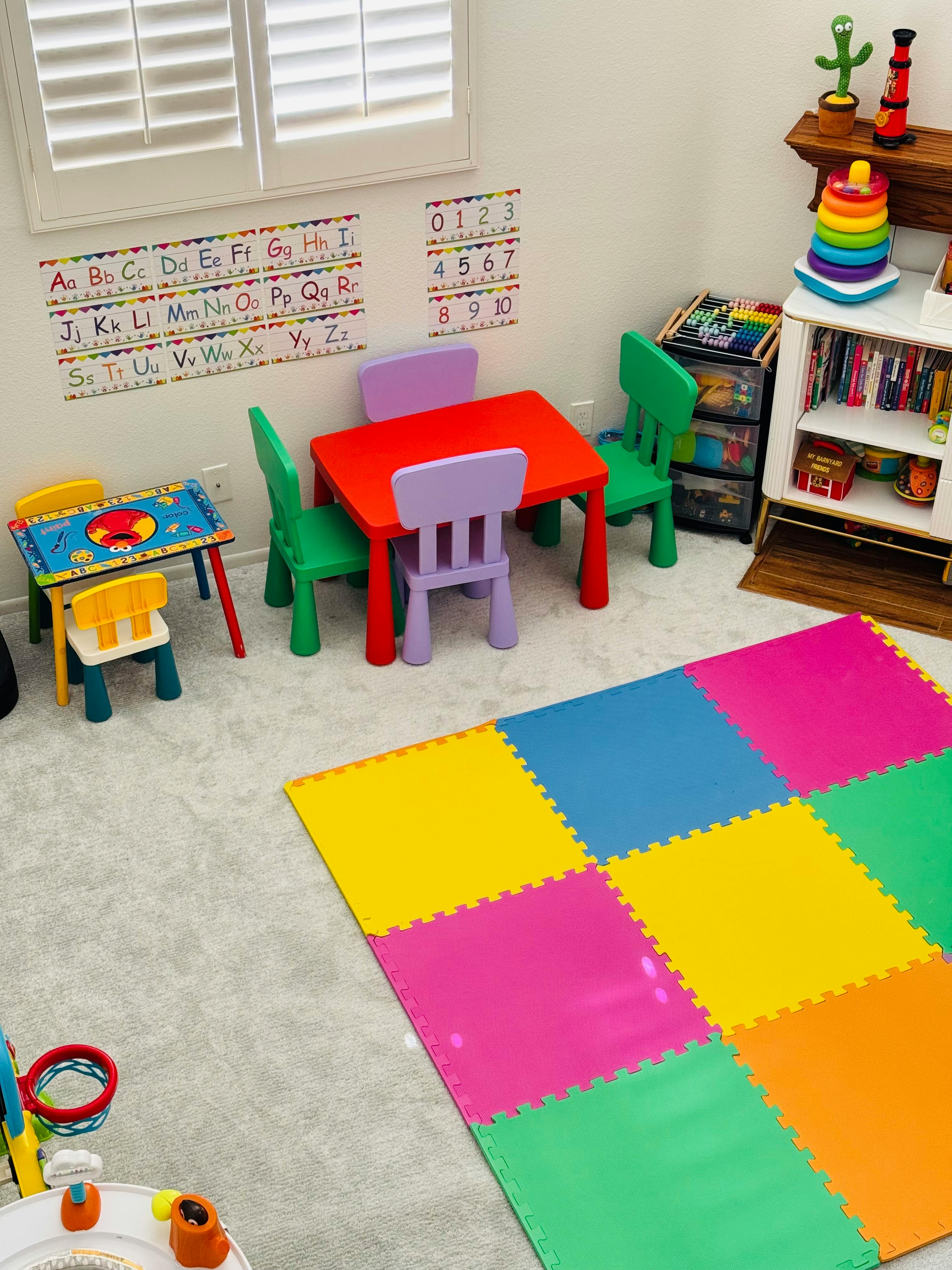 Children's play area with small tables, chairs, and a colorful floor mat