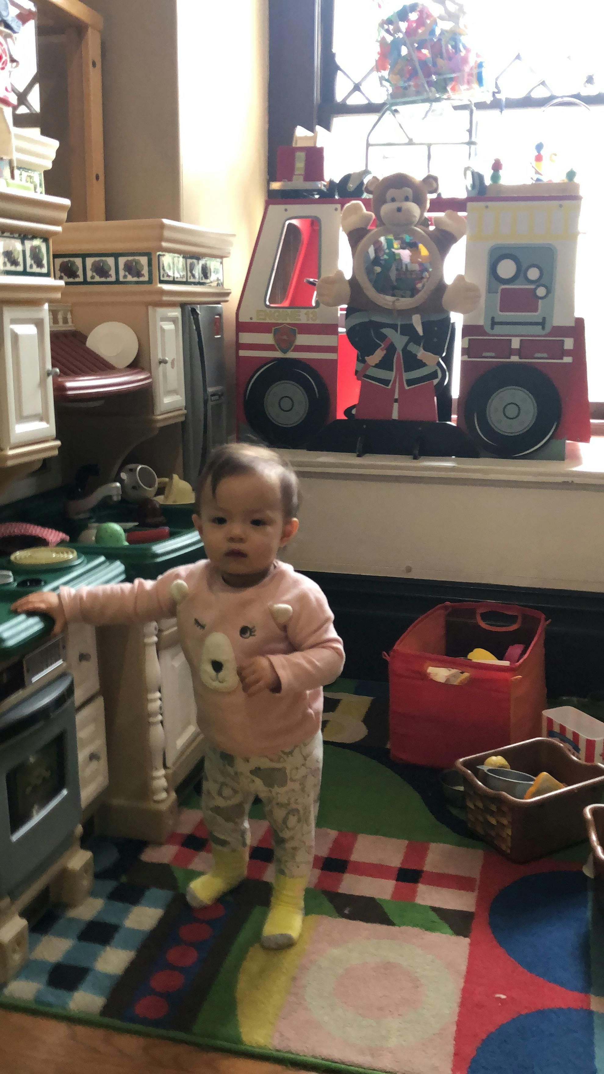 Child standing in a play kitchen