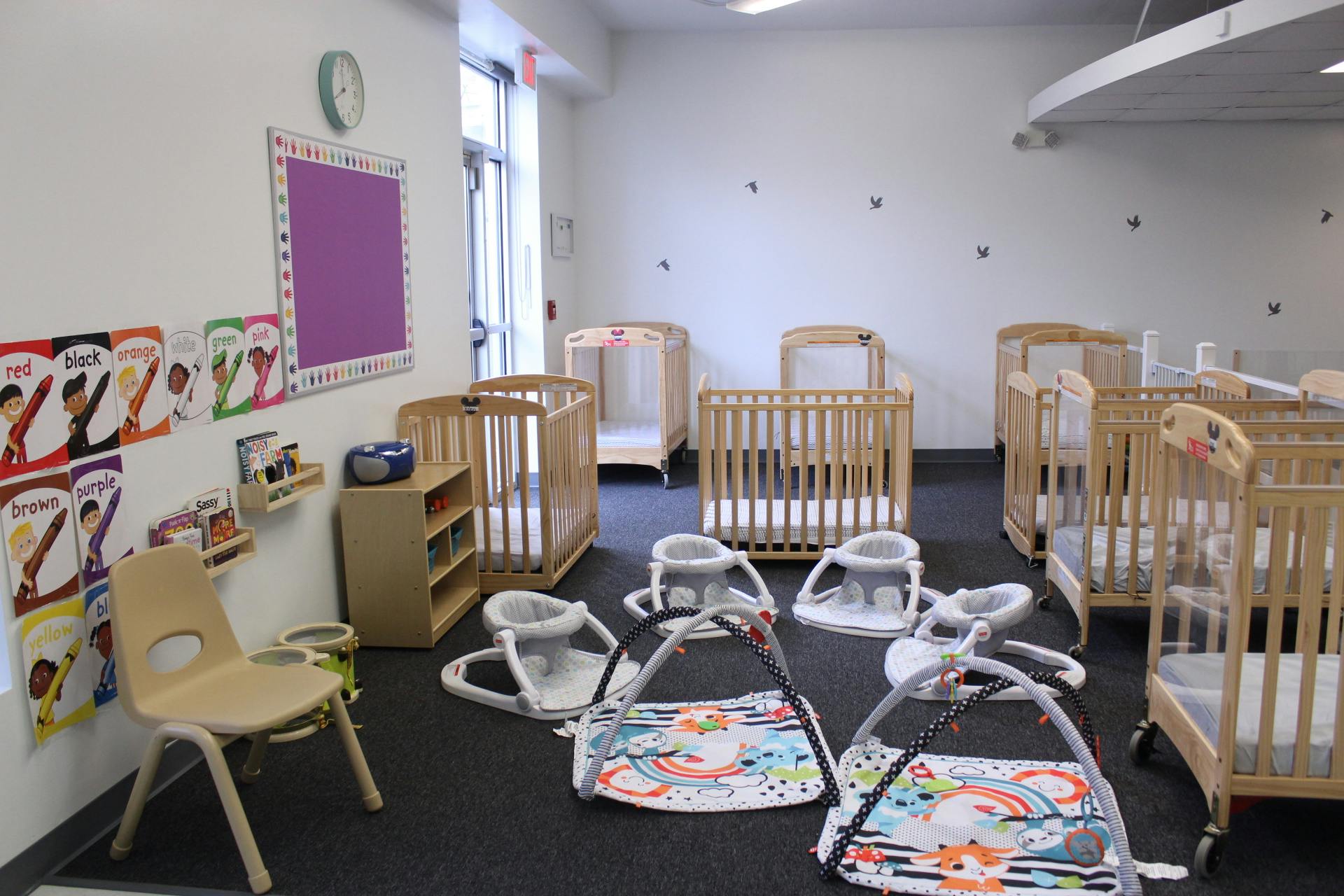 Nursery room with multiple cribs, baby seats, and play mats