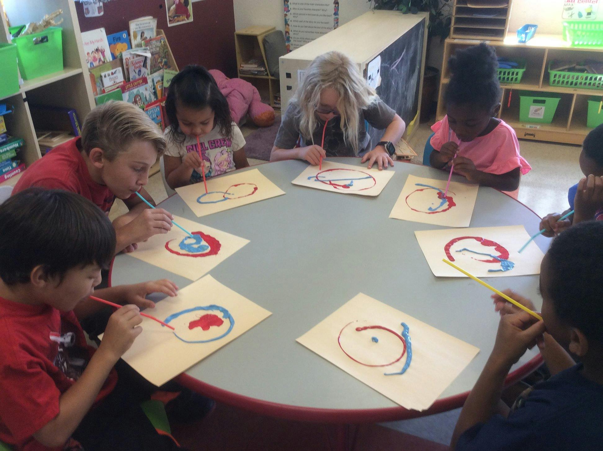 Children painting at a round table in a classroom