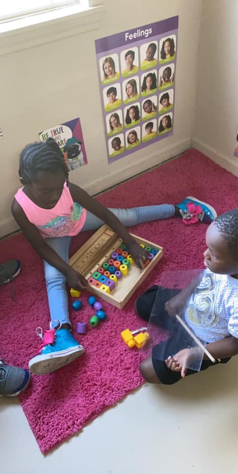 Two children playing with colorful blocks on a pink rug
