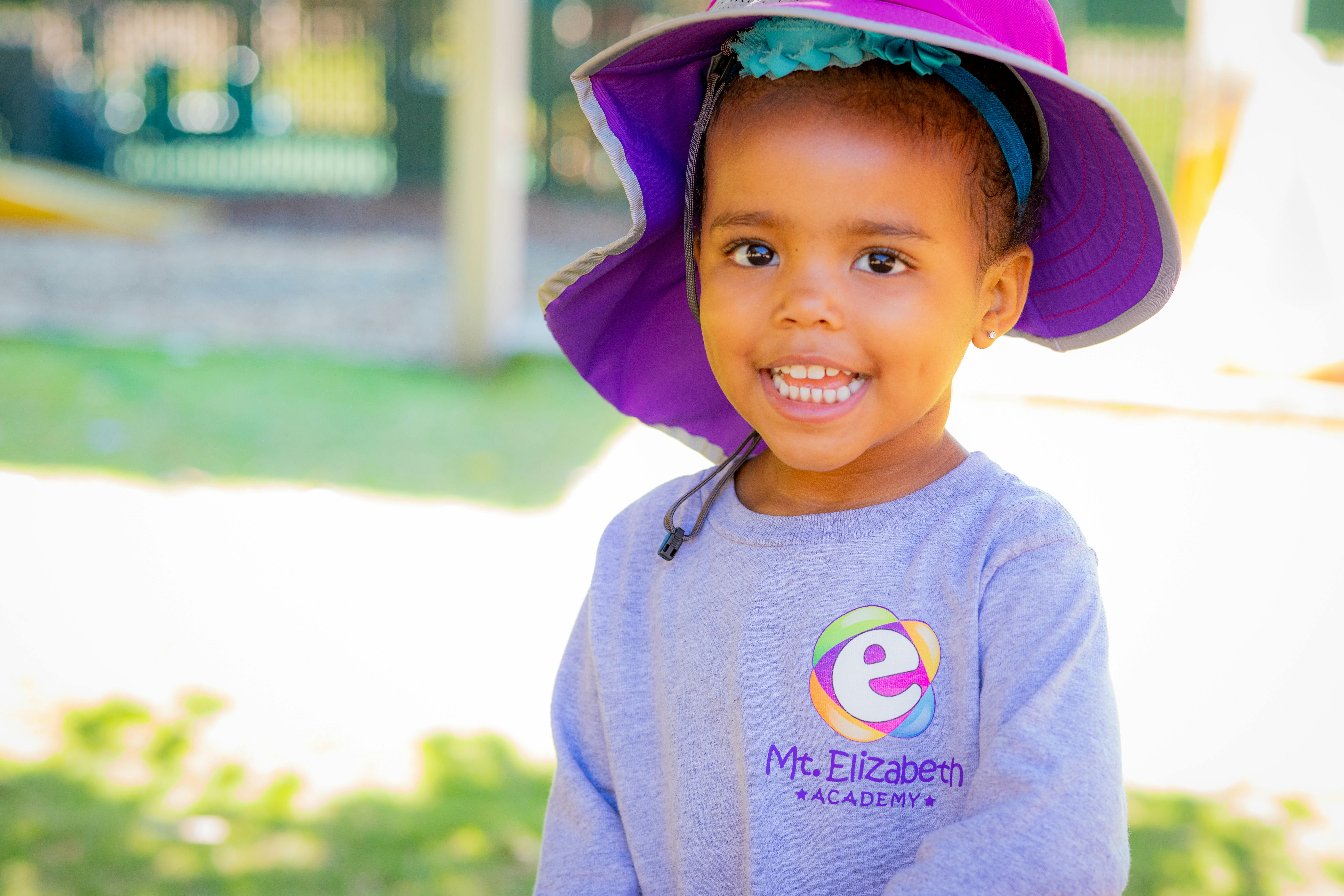 Child wearing a purple hat and a gray shirt