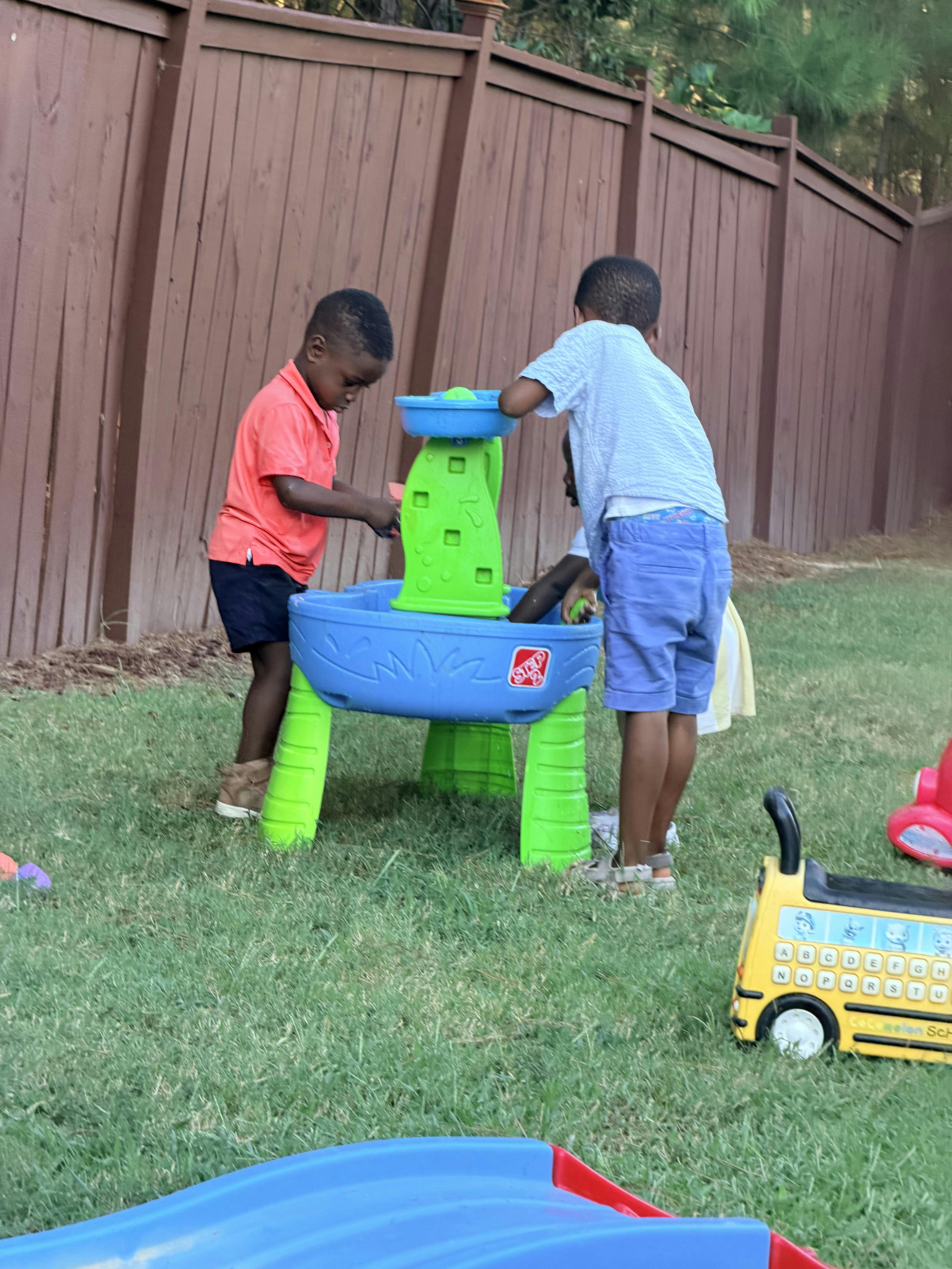 Children playing with a water table in a backyard