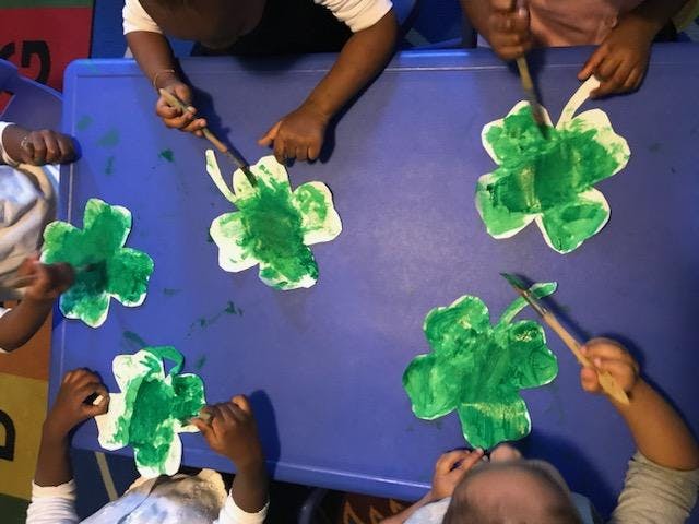 Children painting shamrocks green at a table