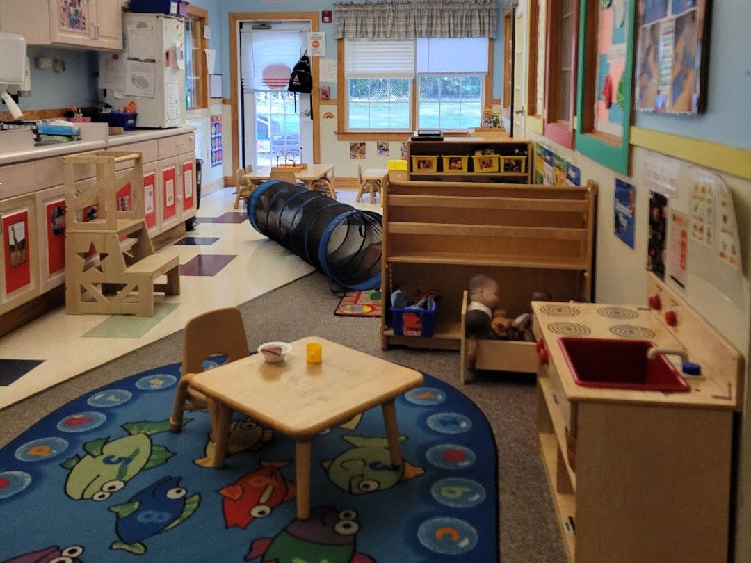 Classroom with play kitchen, small tables, and tunnel