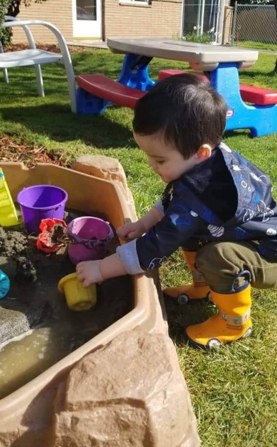 Child playing in a sandbox with water and toys