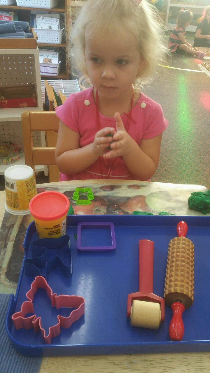 Child playing with modeling clay and cookie cutters