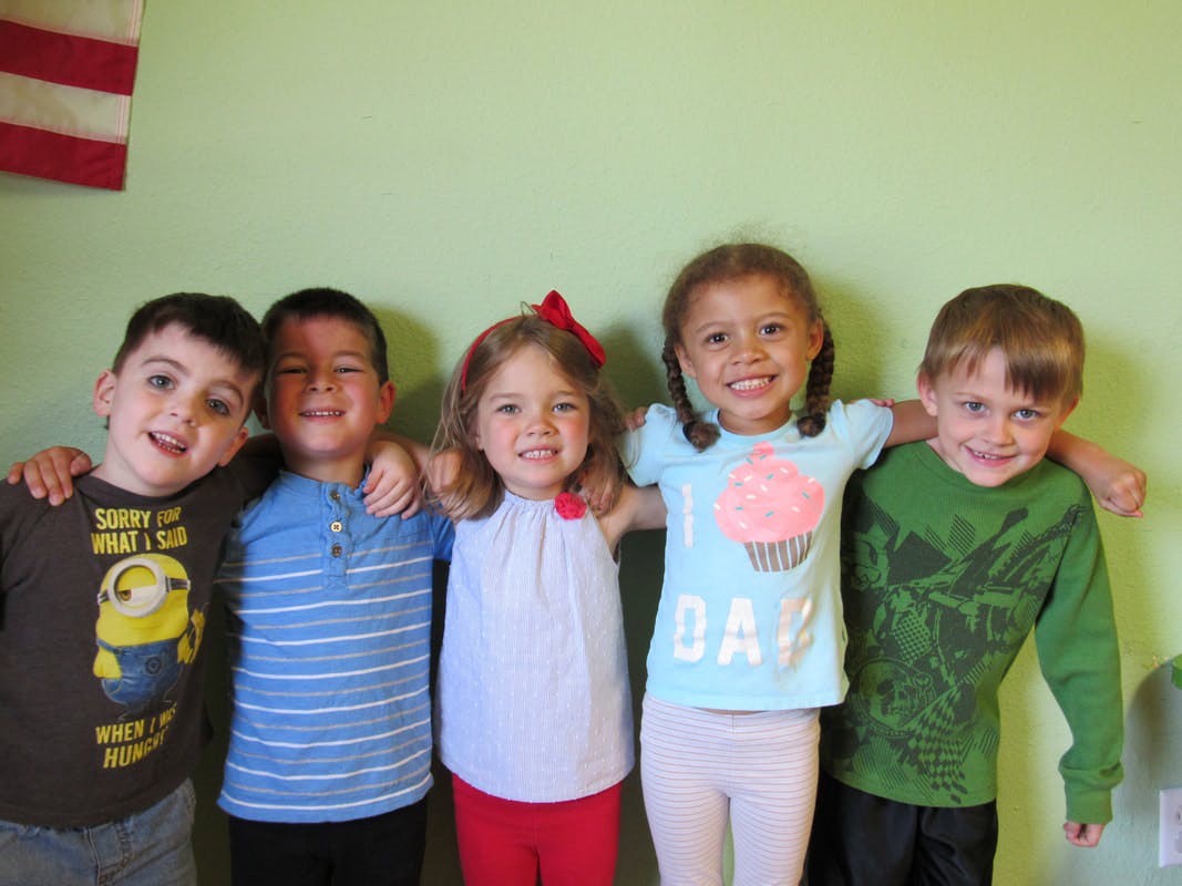 Five children standing with arms around each other