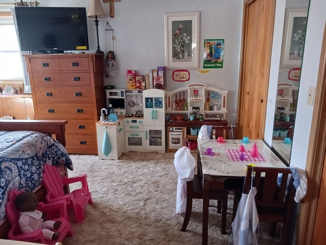 Child-sized play kitchen and dining table with toy tea set in a room