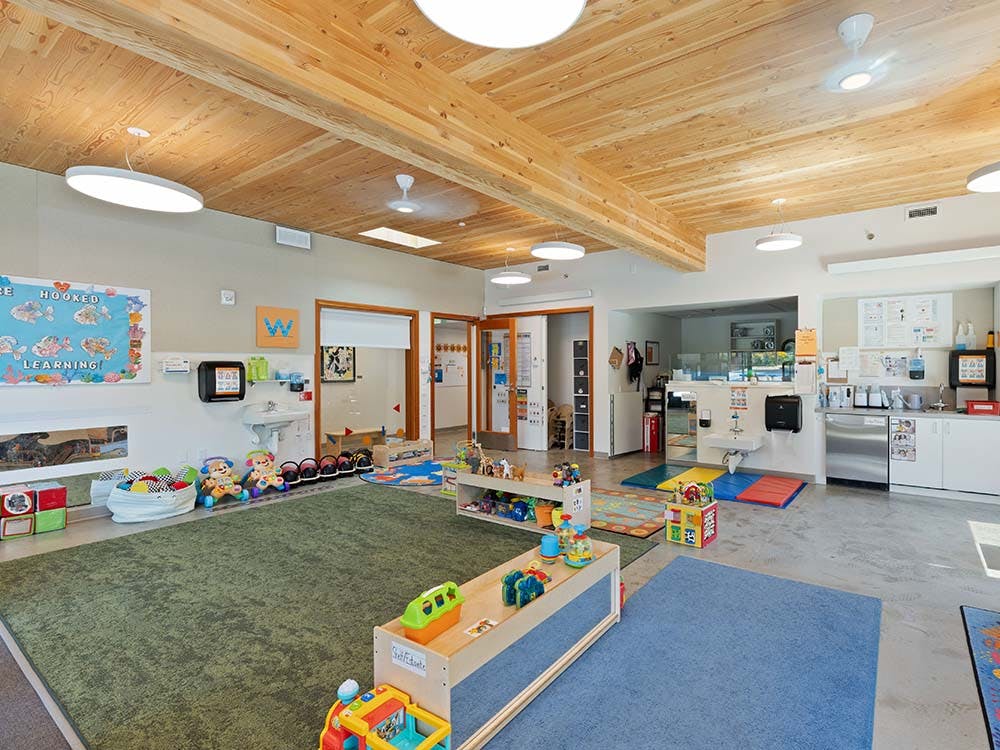 Colorful playroom with a wooden ceiling and toys, with a sink and cabinets