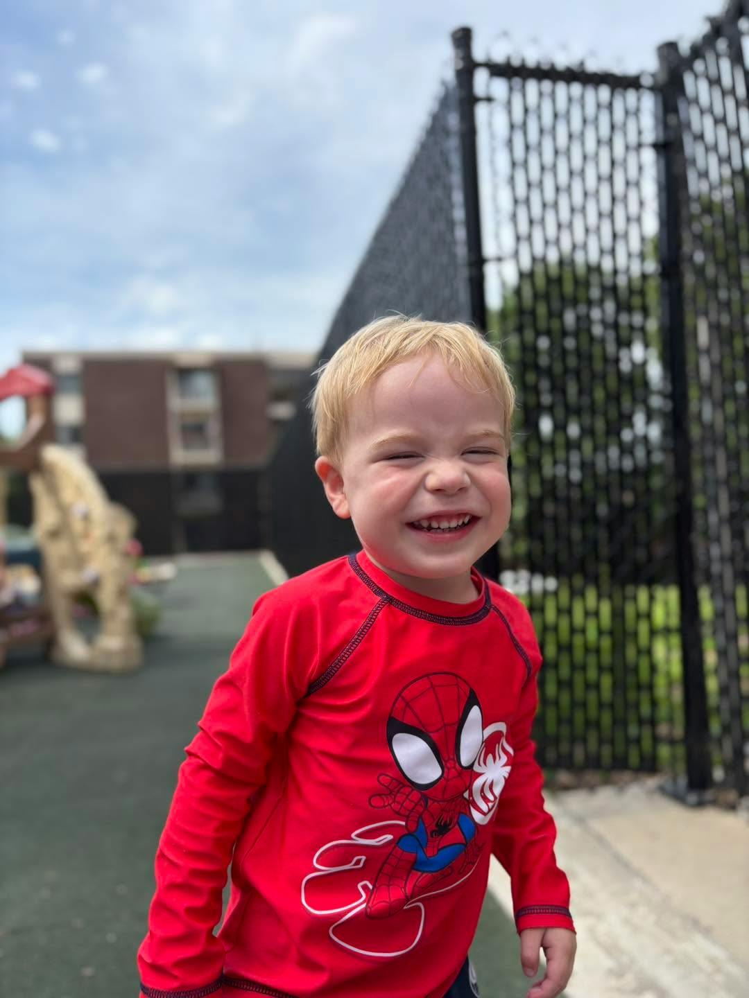 Child in a red Spider-Man shirt with a wide grin