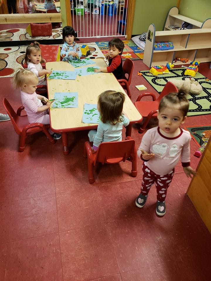 Children sitting at a table with papers and one child standing