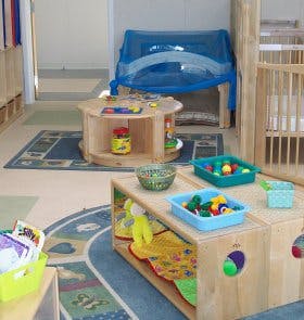Playroom with wooden furniture, toys, and a blue rug
