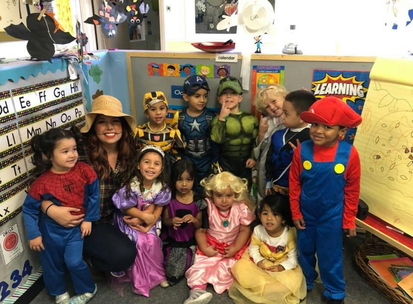Adult and children in costumes posing for a photo in a classroom