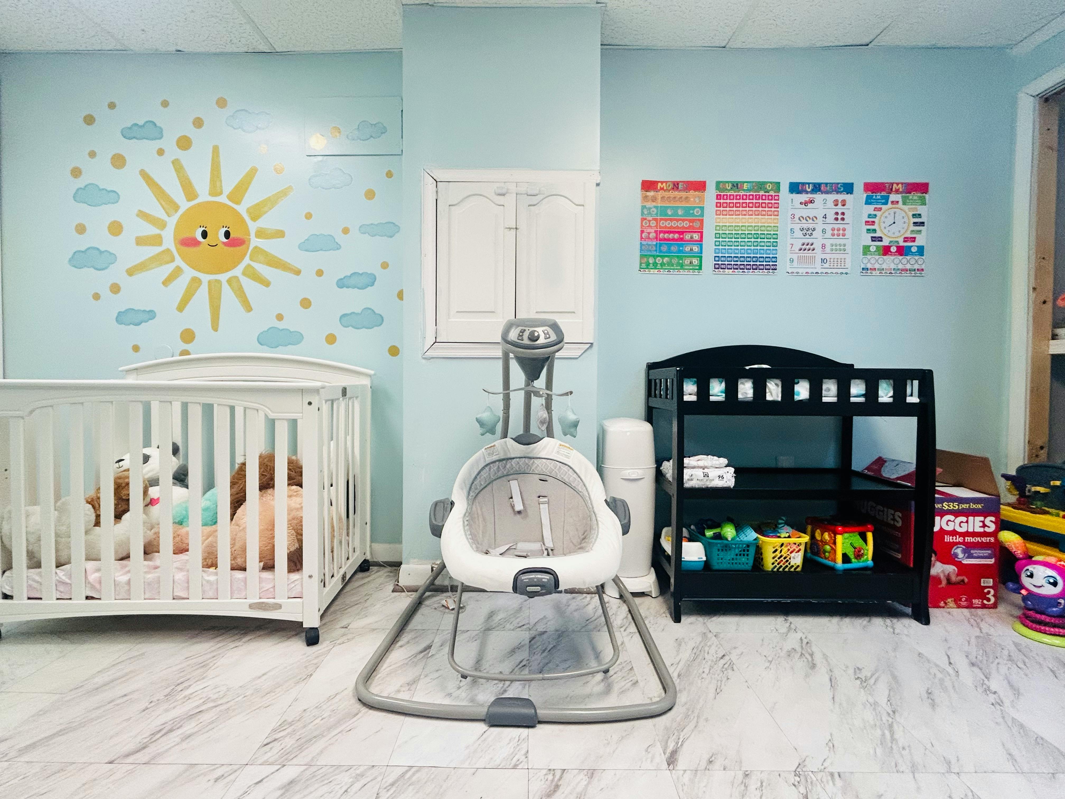 Baby nursery with a crib, infant swing, and changing table against a blue wall