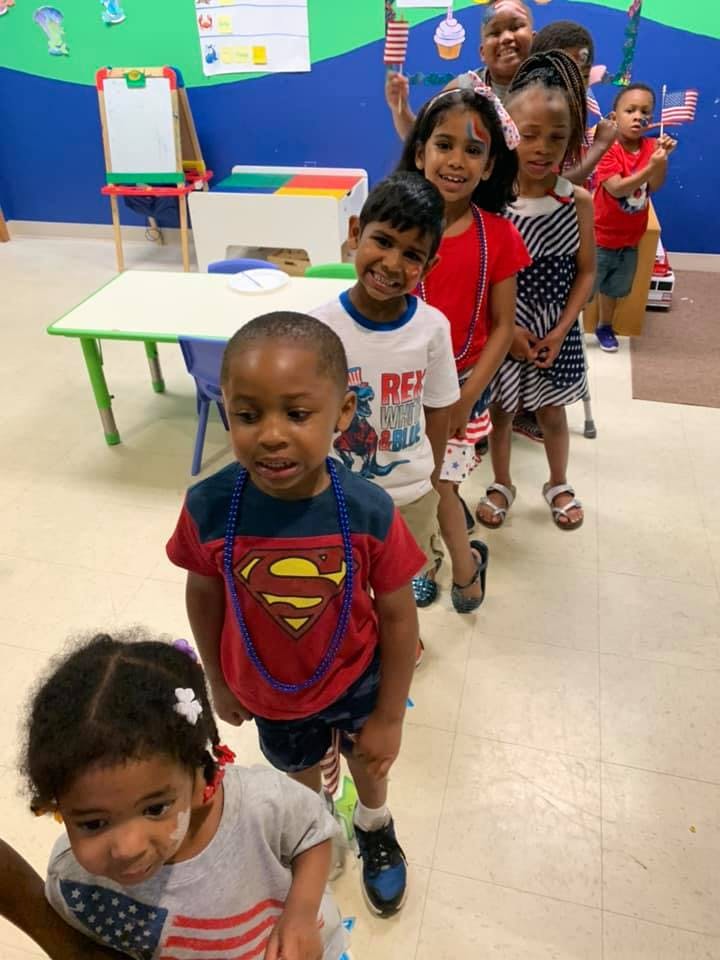 Children in a line, some holding small American flags