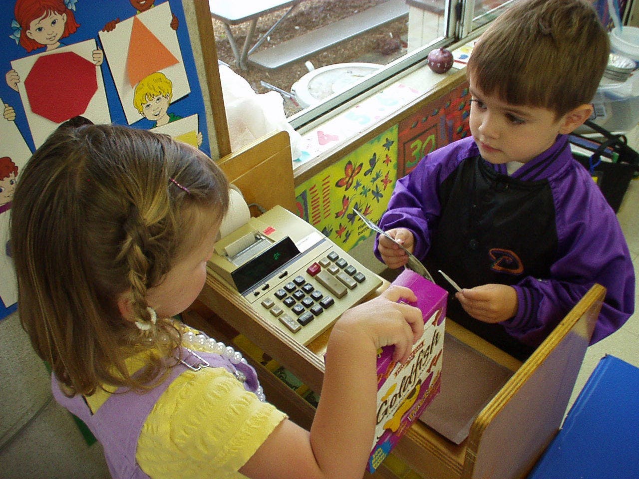 Two children playing with a toy cash register