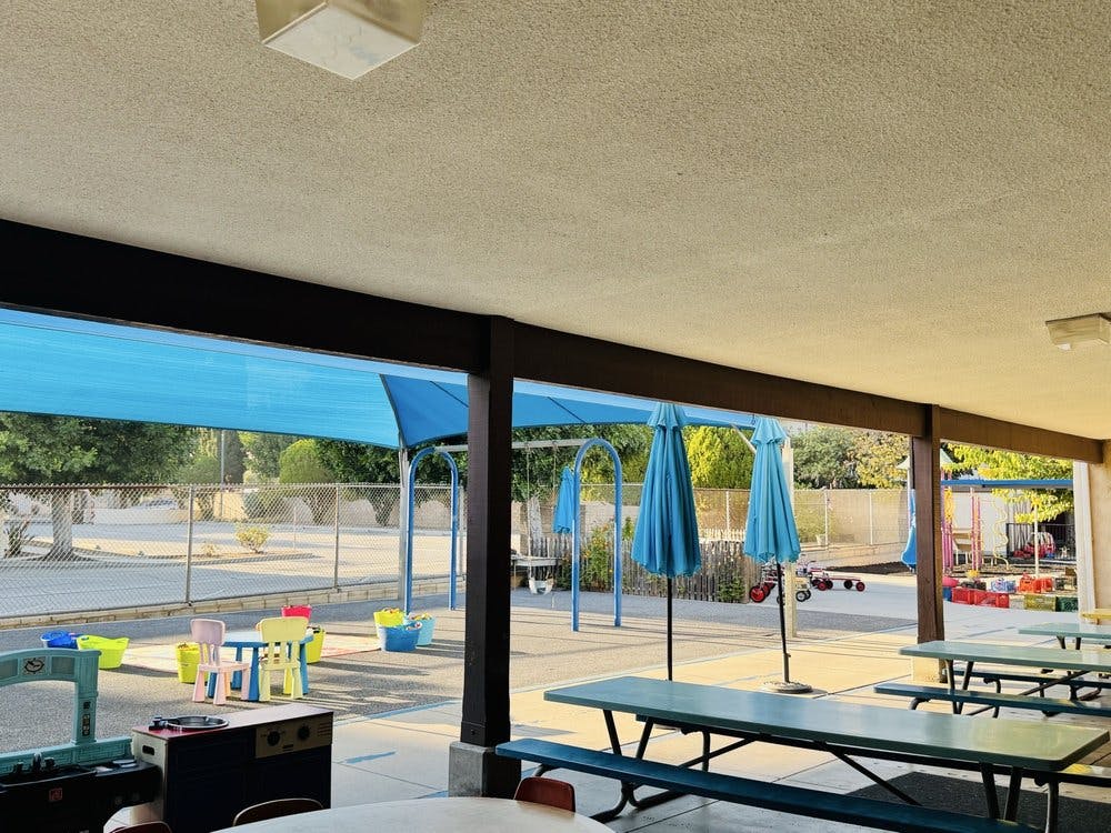 Outdoor patio with picnic tables and blue shade structures
