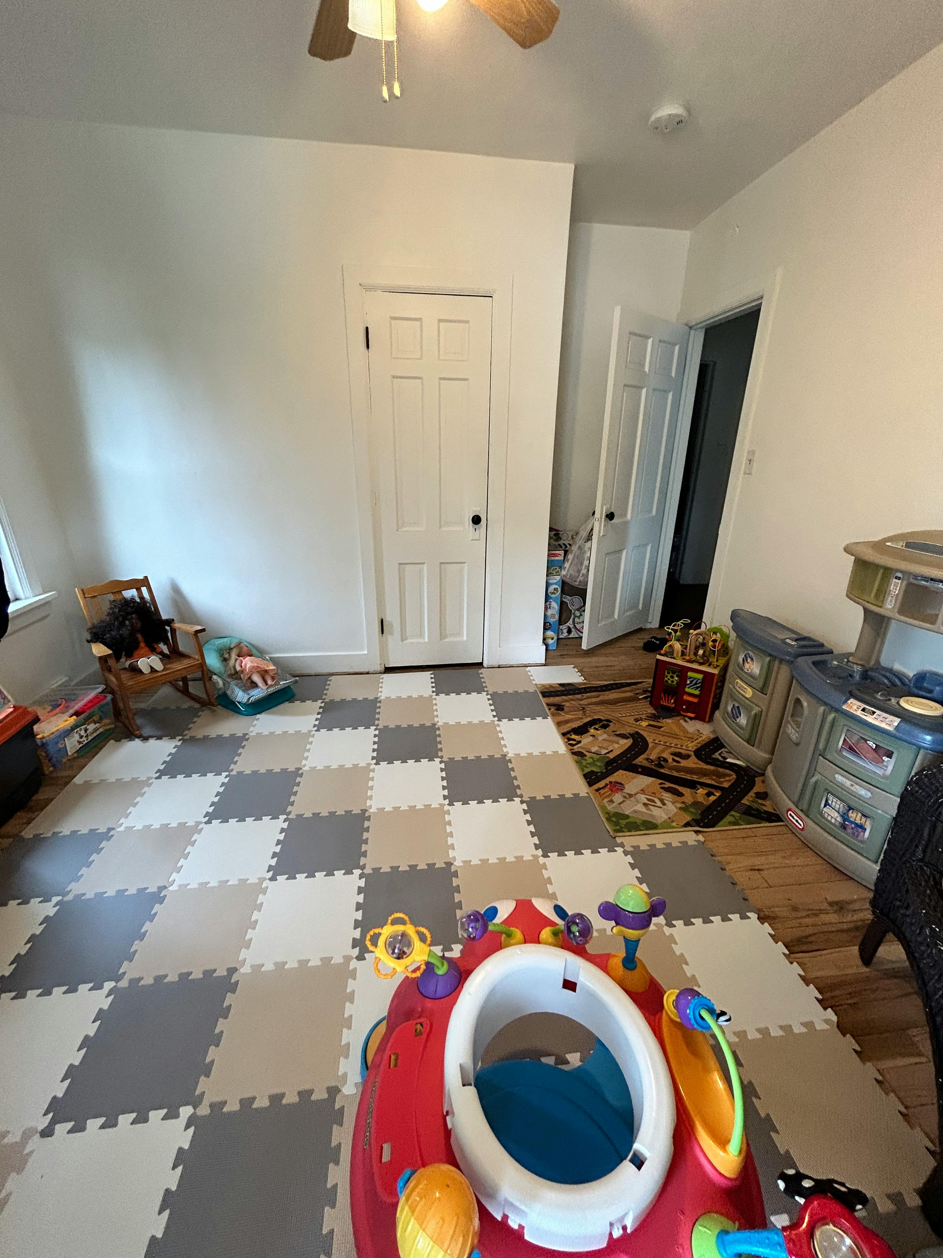 Room with checkered foam floor tiles and baby play equipment