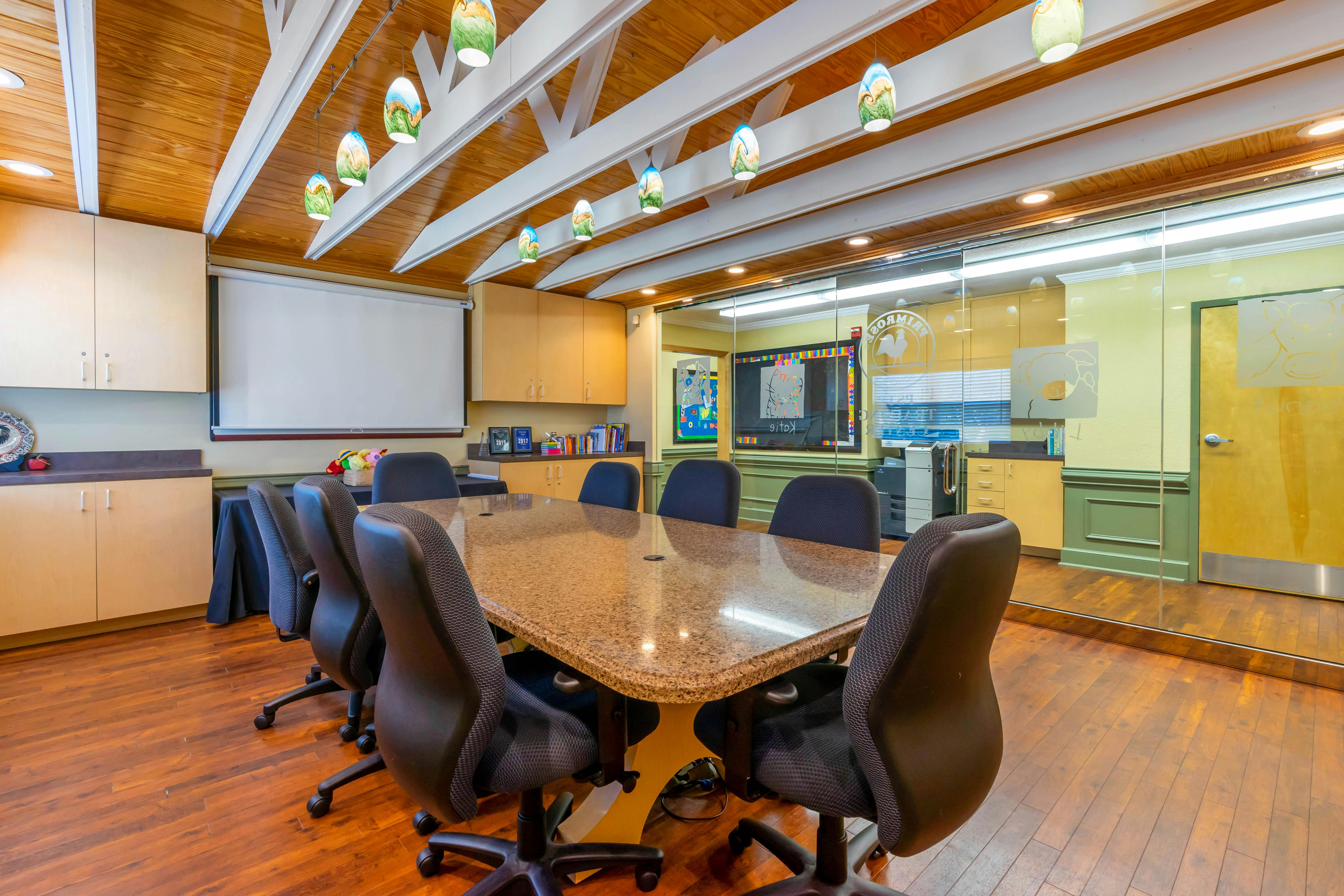 Empty conference room with a large table, chairs, projection screen, and cabinets