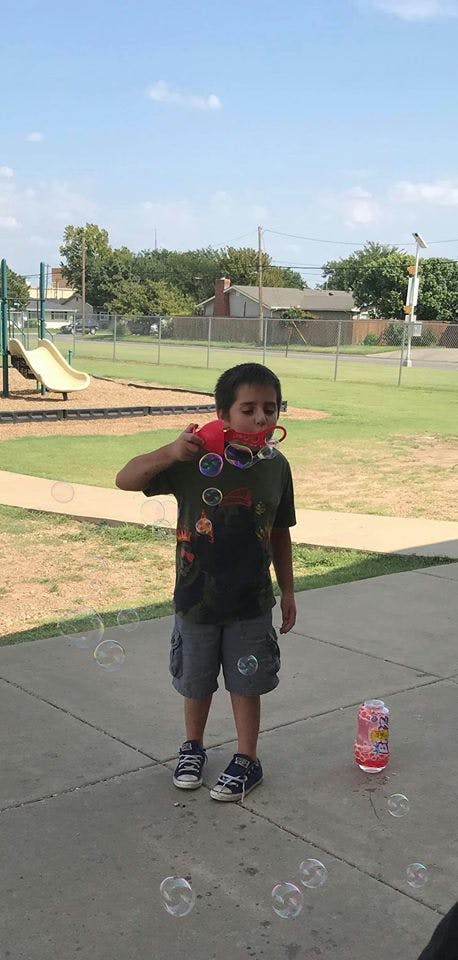 Child blowing bubbles with a bubble wand at a playground