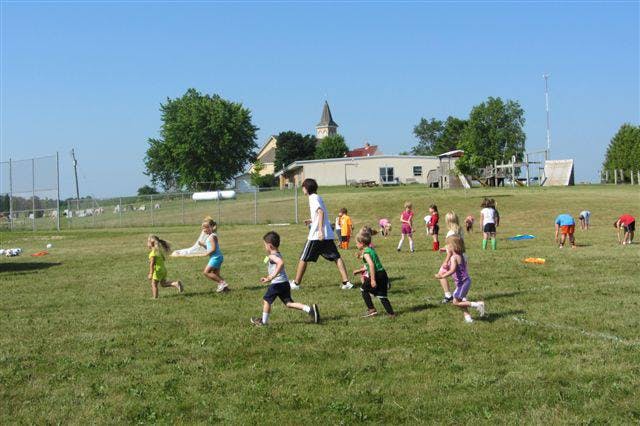 Children and adults playing soccer on a grassy field