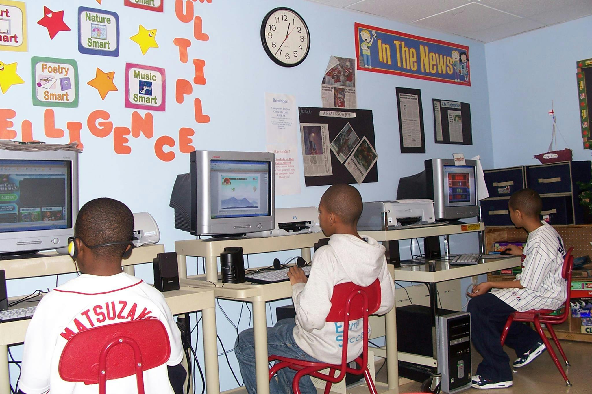 Three children sitting at computers in a classroom