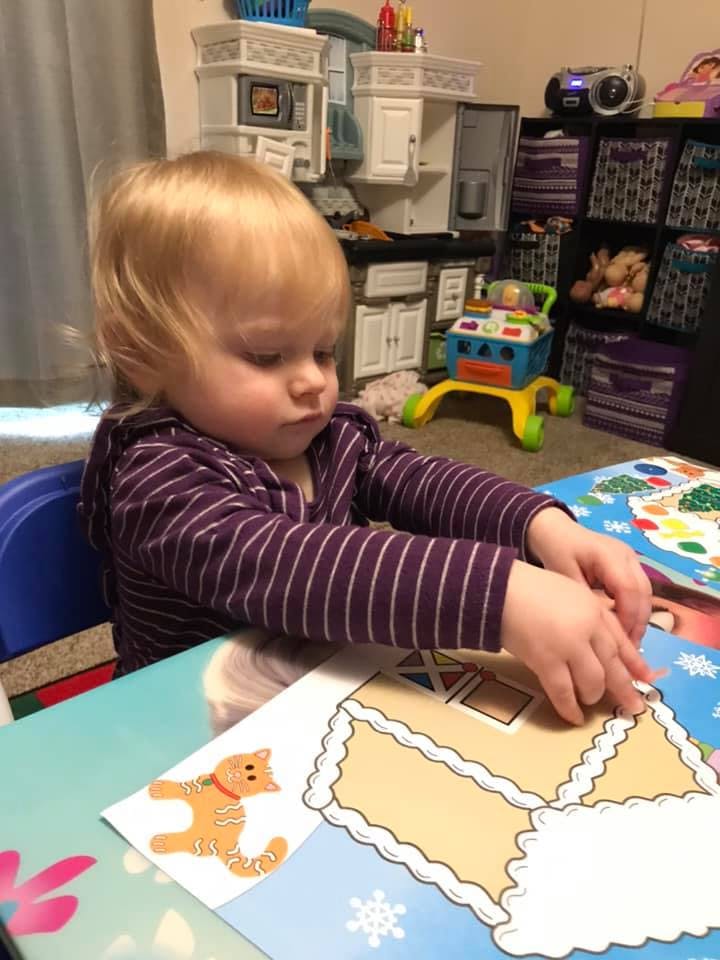 Child playing with a gingerbread house sticker