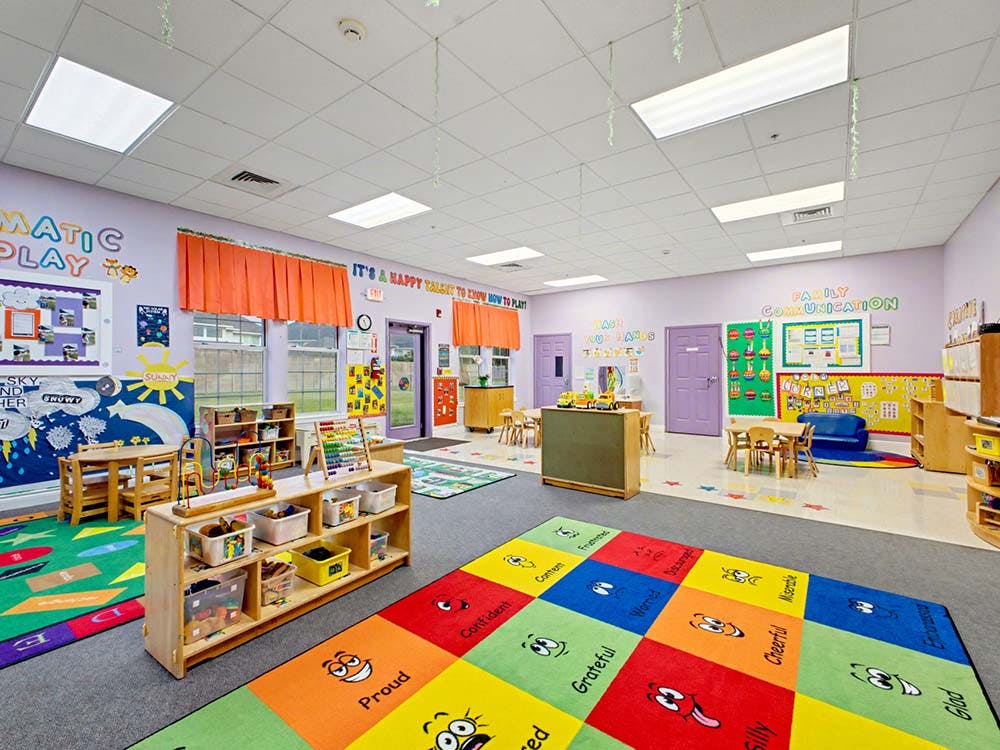 Colorful early childhood classroom with small tables, chairs, and play areas