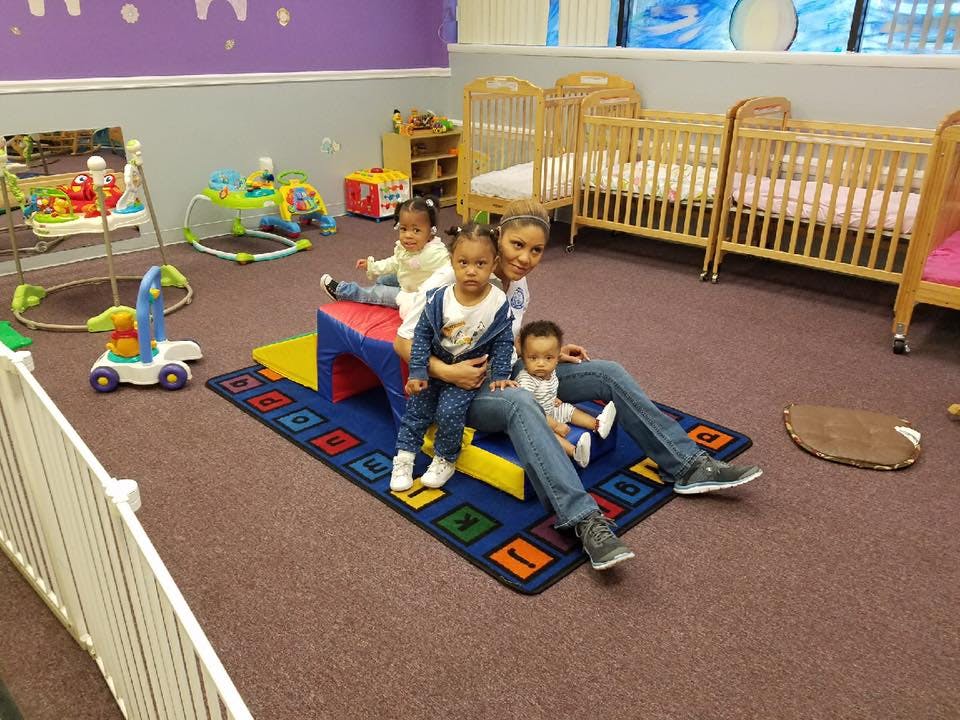 Person sitting on floor with three children in a play area