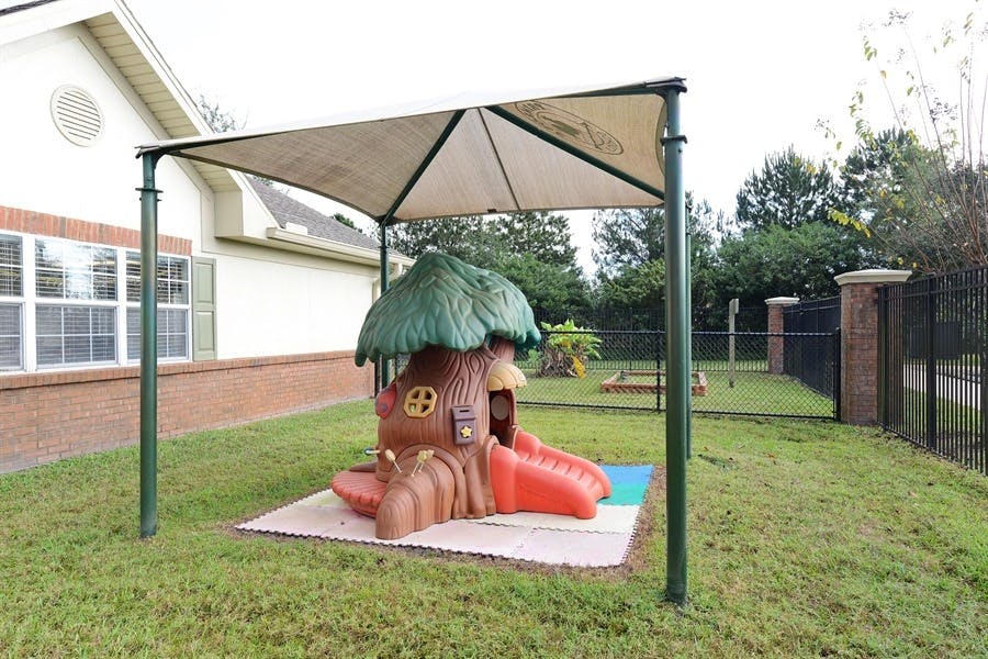 Playground with a treehouse-shaped slide under a shade canopy