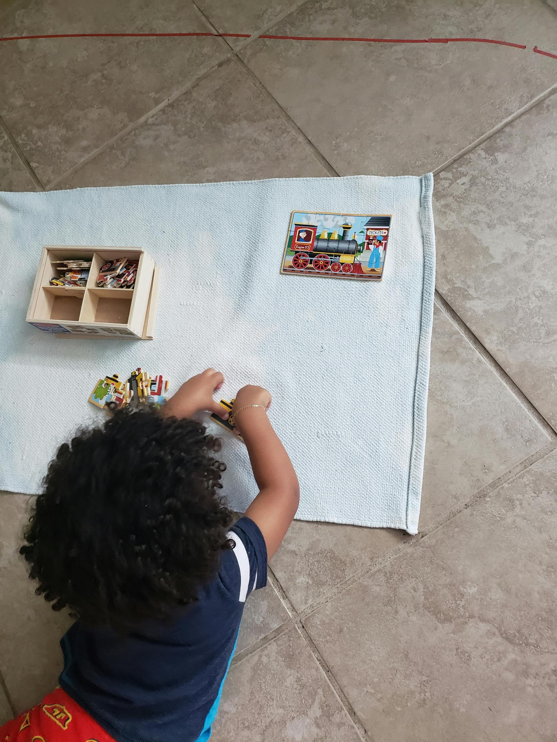 Child playing with puzzle pieces on a blanket