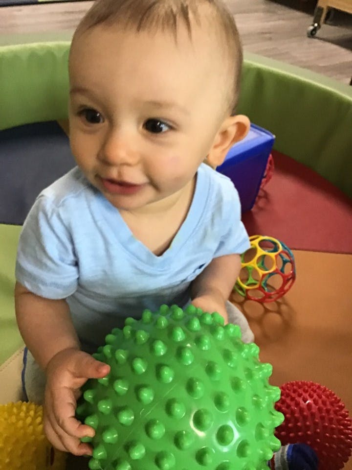 Child holding a green spiky ball