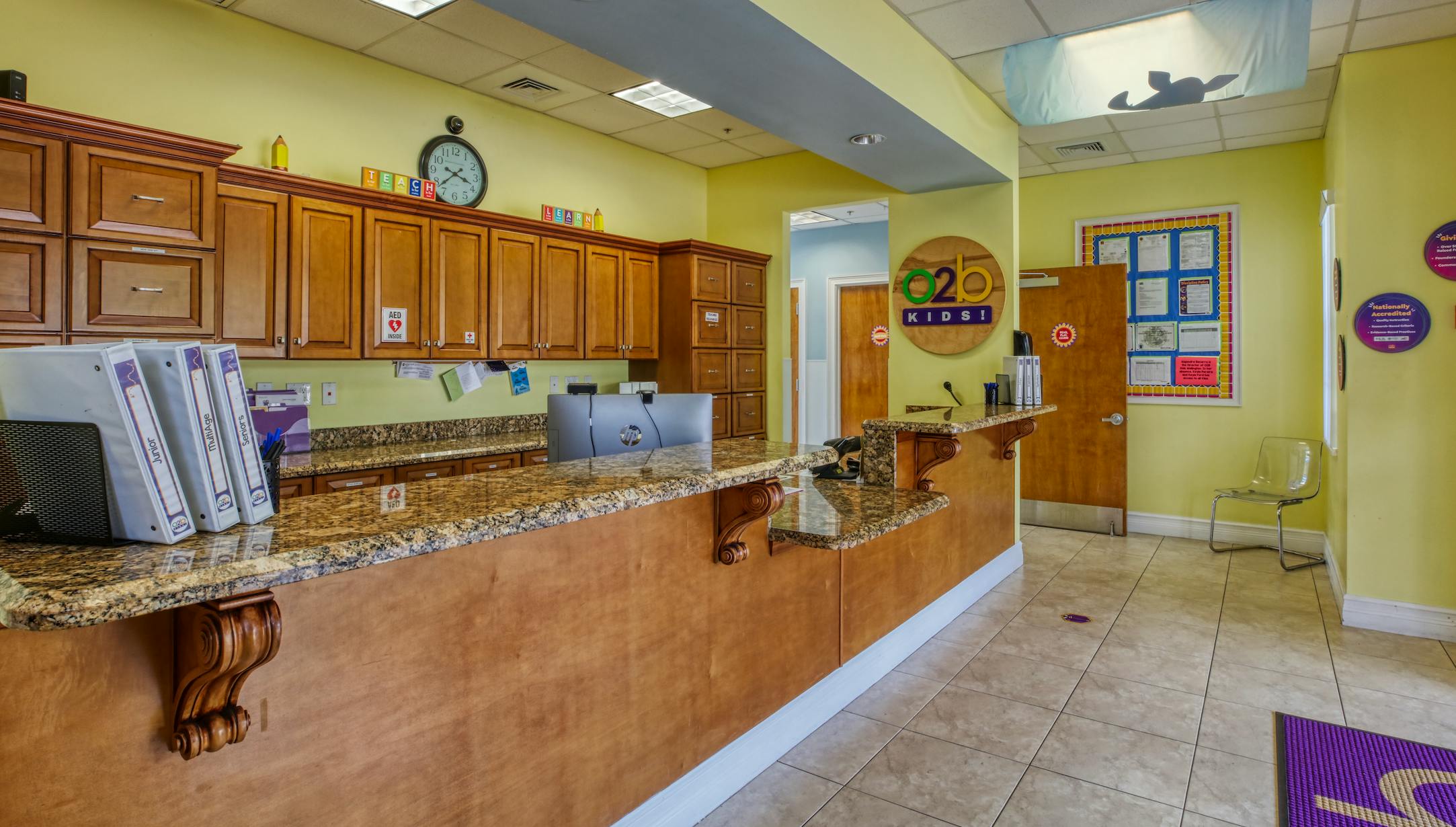 Reception desk with wood cabinets and granite countertops, binders, and a computer monitor