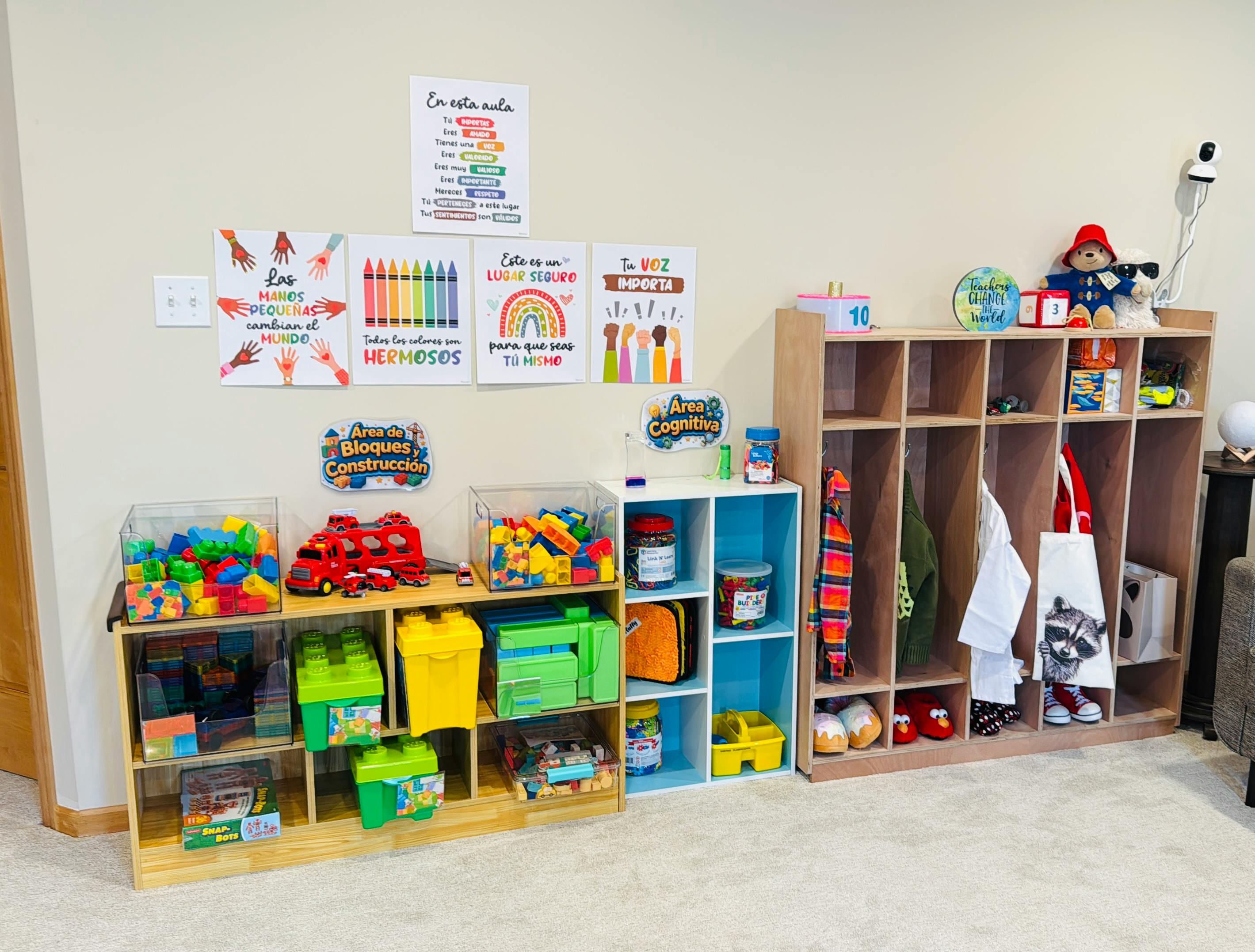 Classroom wall with Spanish posters, storage shelves with toys, and cubbies