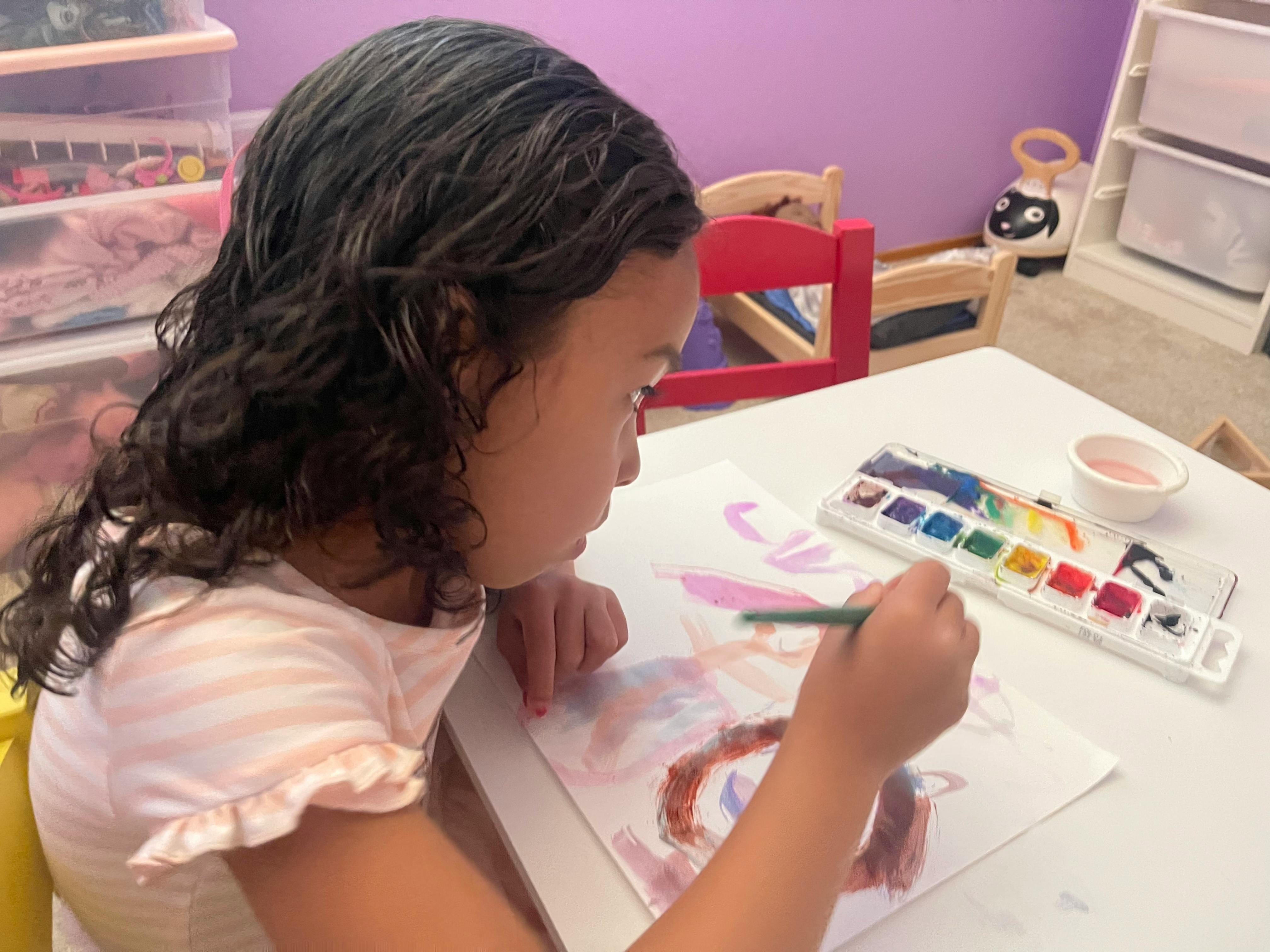Child painting with watercolors at a table