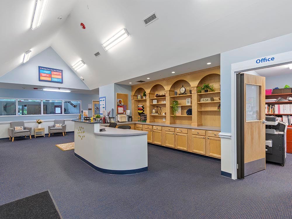 Reception desk with office door, storage shelves, and two chairs in a waiting area