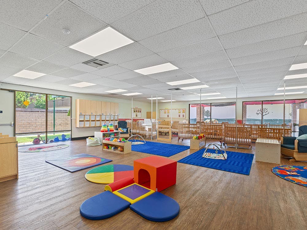 daycare classroom with multiple cribs, playmats, and toys