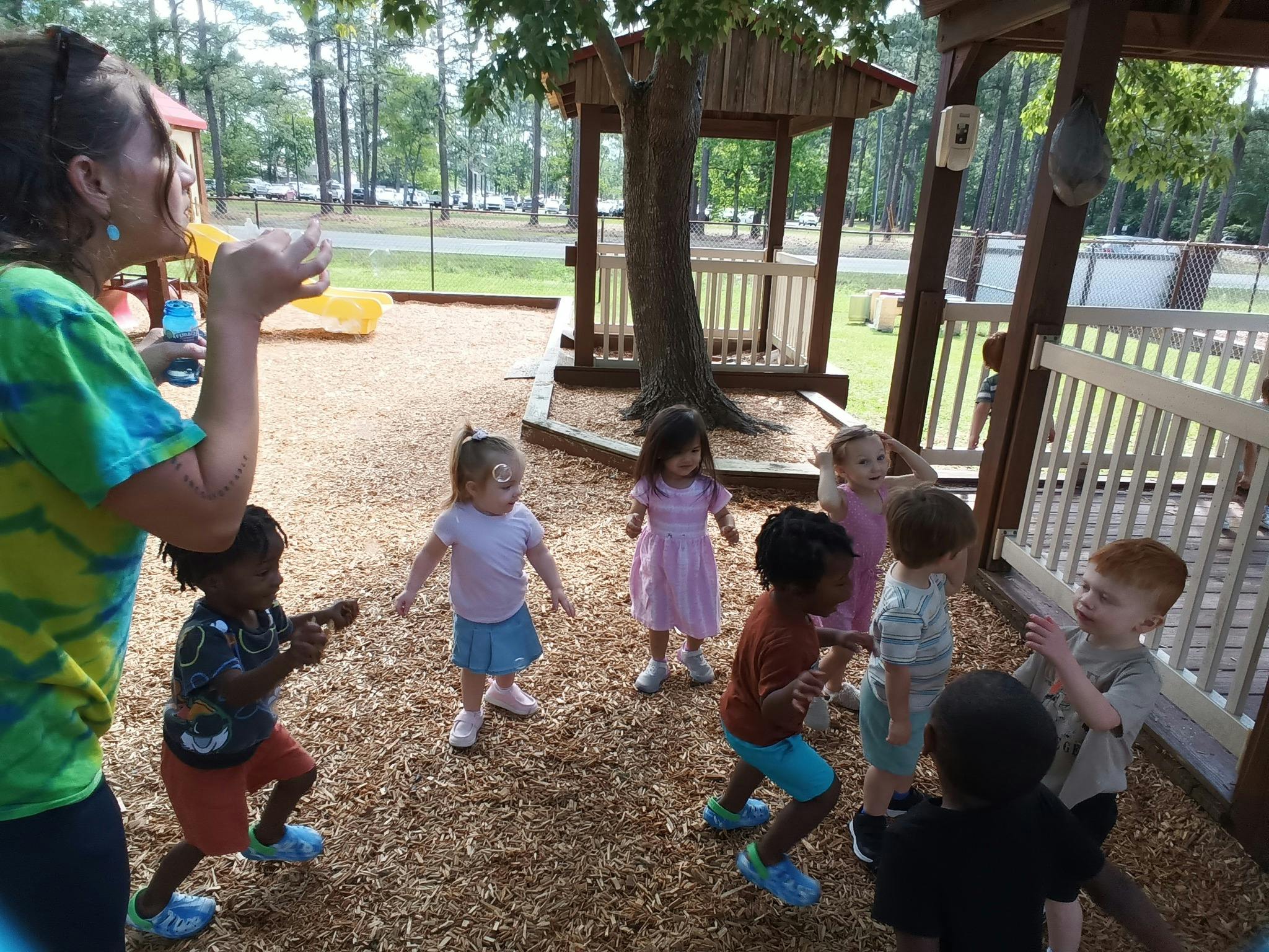 Person blowing bubbles for a group of children on a playground