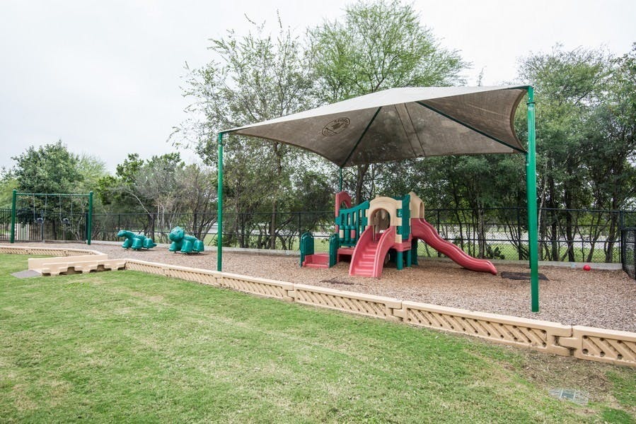 Playground with slides and climbing structures under a shade canopy