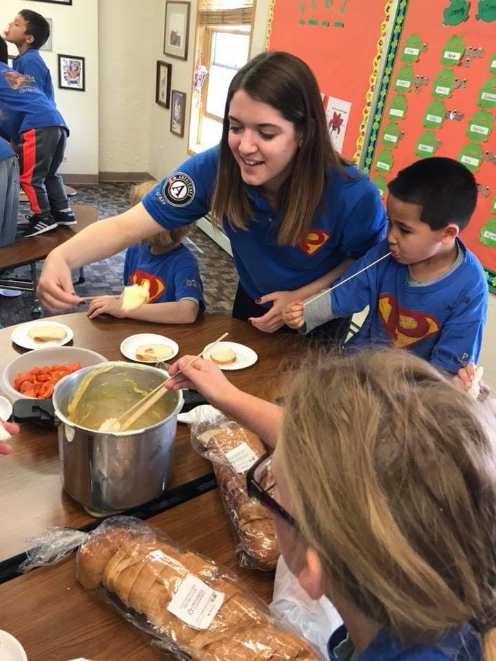 Person helping children with food at a table